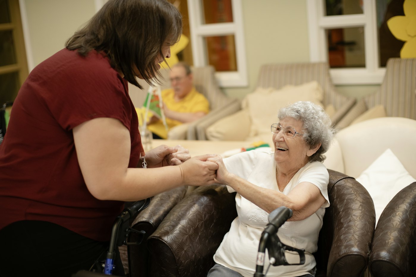 A caregiver helping an older woman stand up with her walker
