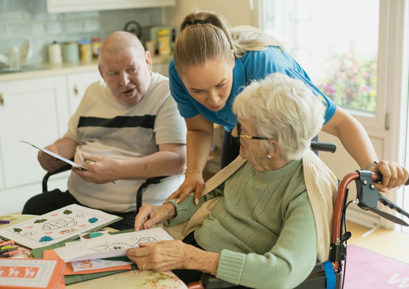 A caregiver doing a colouring activity with older adults at a table