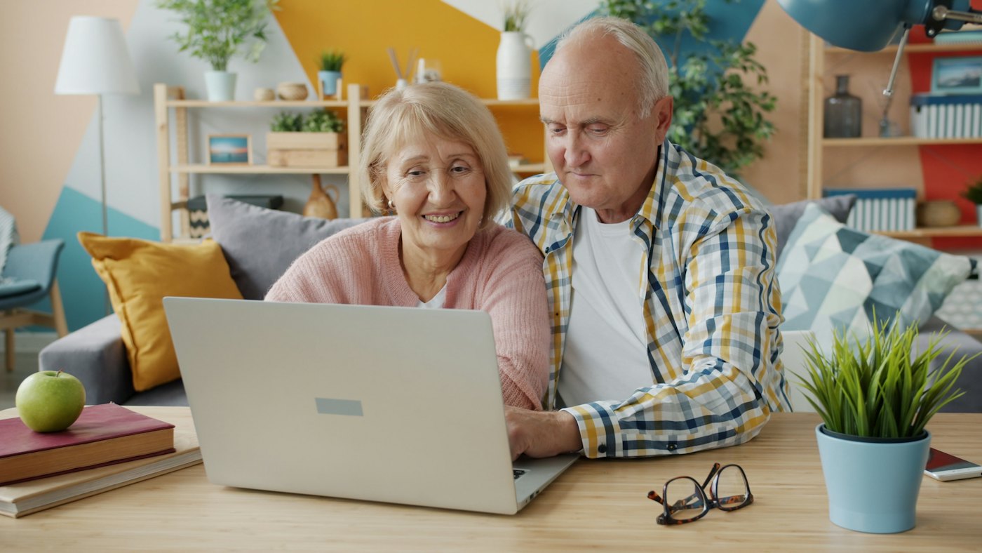 An older couple smiling while using a laptop together at home